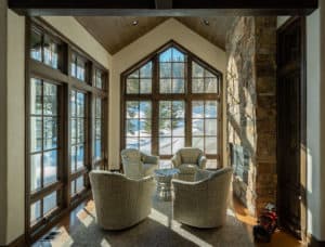Four chairs situated in a beautiful nook with windows on two sides and a fireplace on the other.