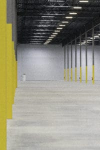 Warehouse support poles lined up to accent the boarders of the image while looking across a large warehouse.